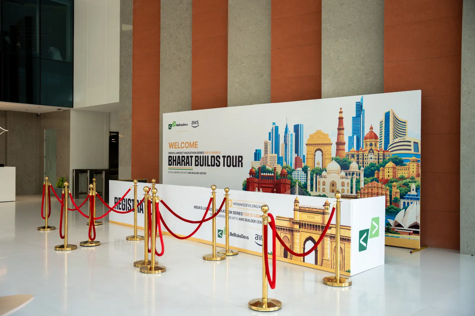 The Bharat Builds Tour registration desk in a marble lobby, ringed by gold stanchions and red ropes before the doors opened