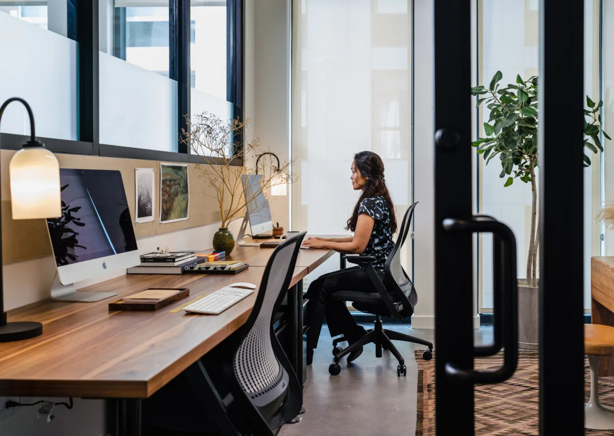 A private office at The Shop, with a walnut desk by floor-to-ceiling windows